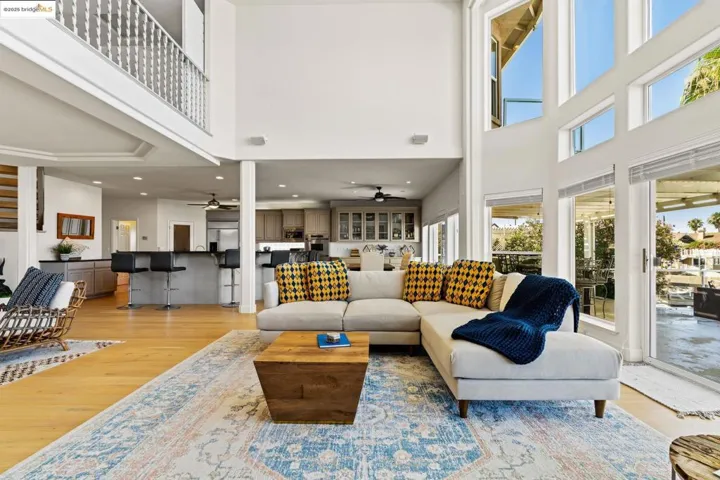 Living room featuring a towering ceiling, light wood-style floors, ceiling fan, and recessed lighting
