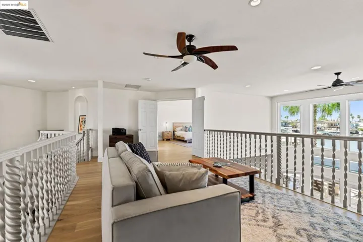 Living area with recessed lighting, ceiling fan, light wood-type flooring, arched walkways, and a water view