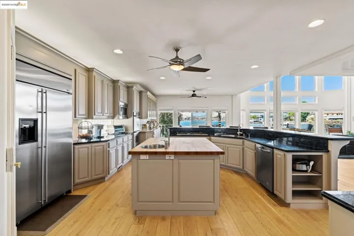 Kitchen featuring gray cabinetry, open shelves, appliances with stainless steel finishes, ceiling fan, and light wood-type flooring