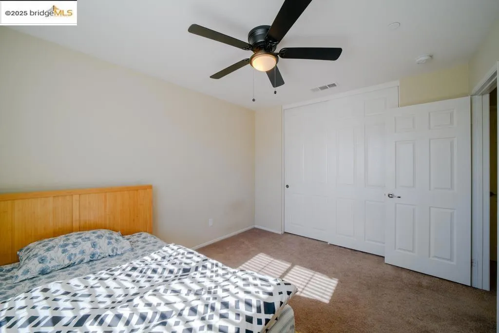 Bedroom featuring light colored carpet, a ceiling fan, and a closet