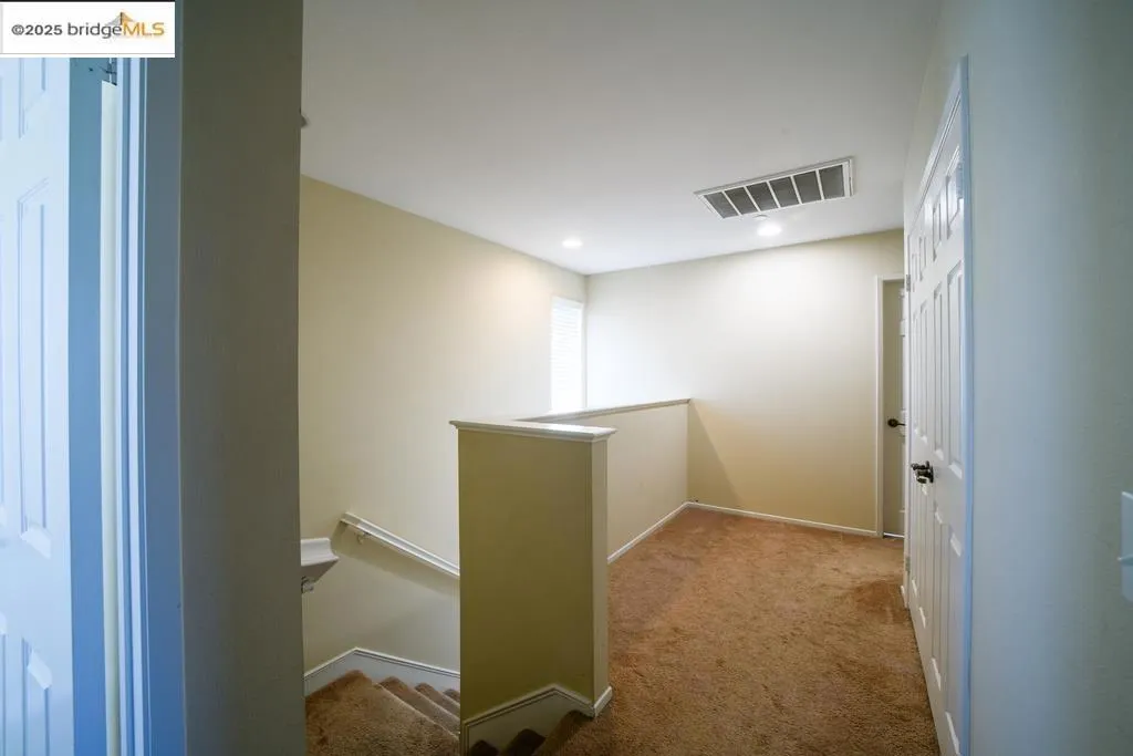Corridor featuring an upstairs landing and light colored carpet