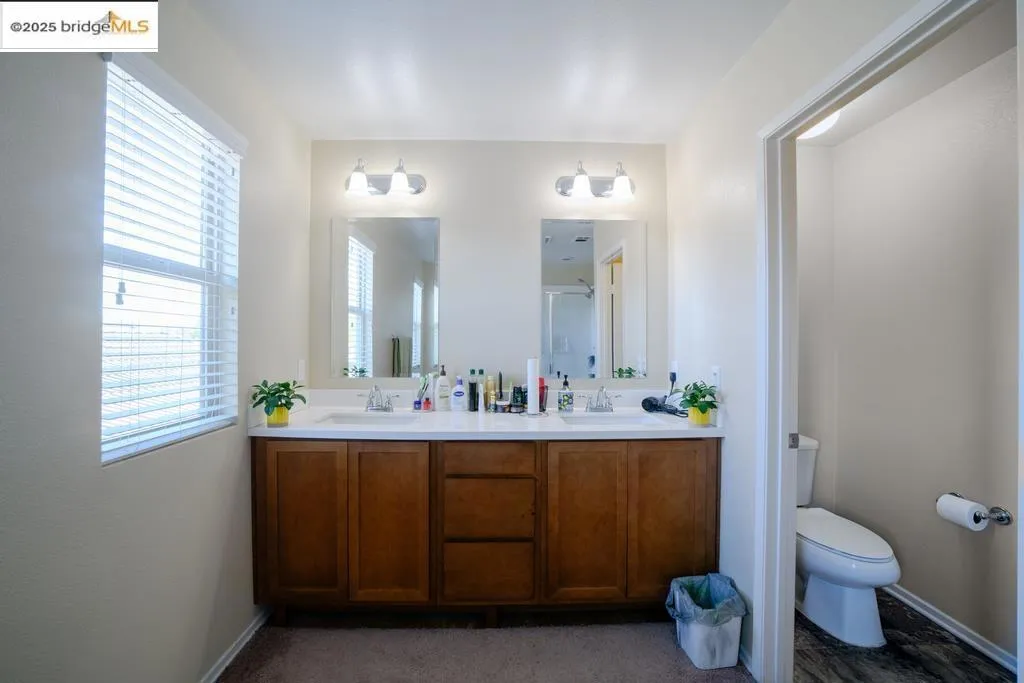 Bathroom with double vanity and dark carpet
