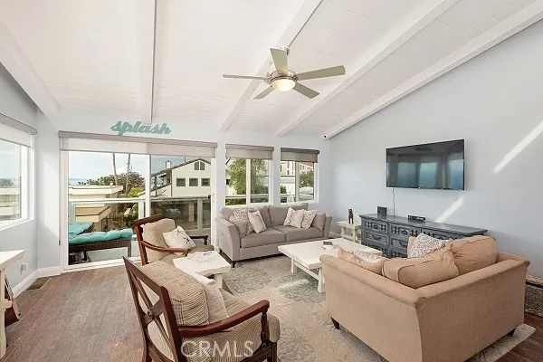 Open living, dining and kitchen space with modern wood-like tile flooring, ceiling fan and beamed ceiling