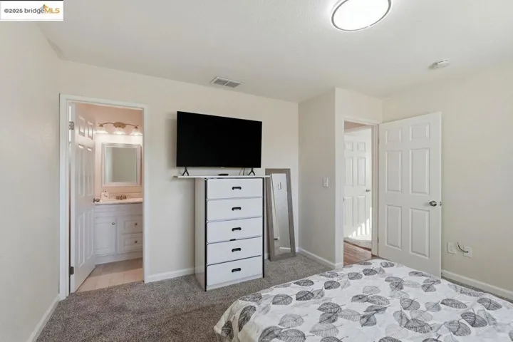 Bedroom with light carpet and ensuite bathroom