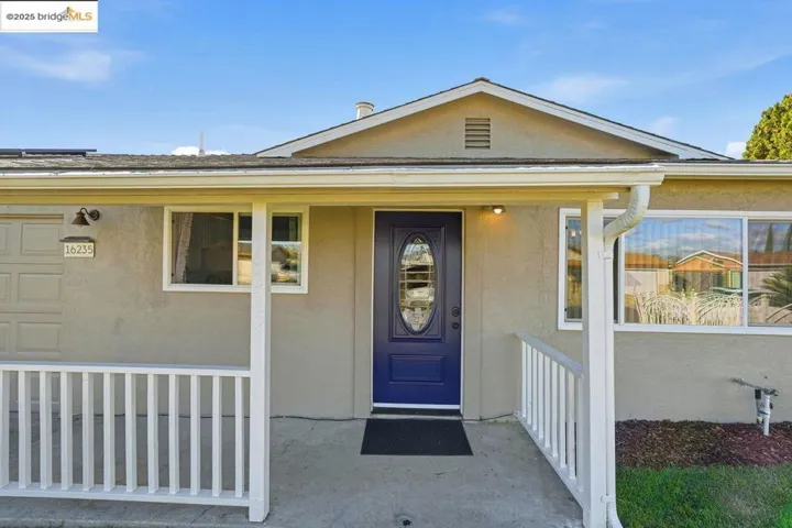 Doorway to property with covered porch and stucco siding