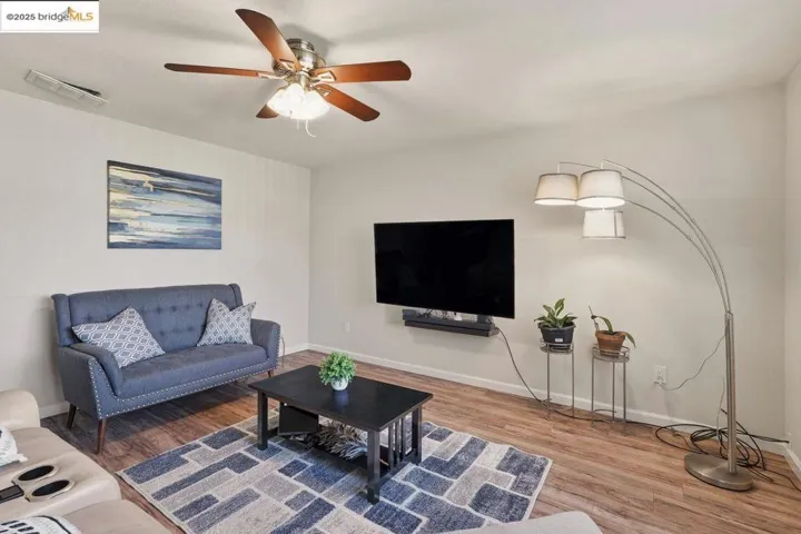 Living room with light wood finished floors and a ceiling fan