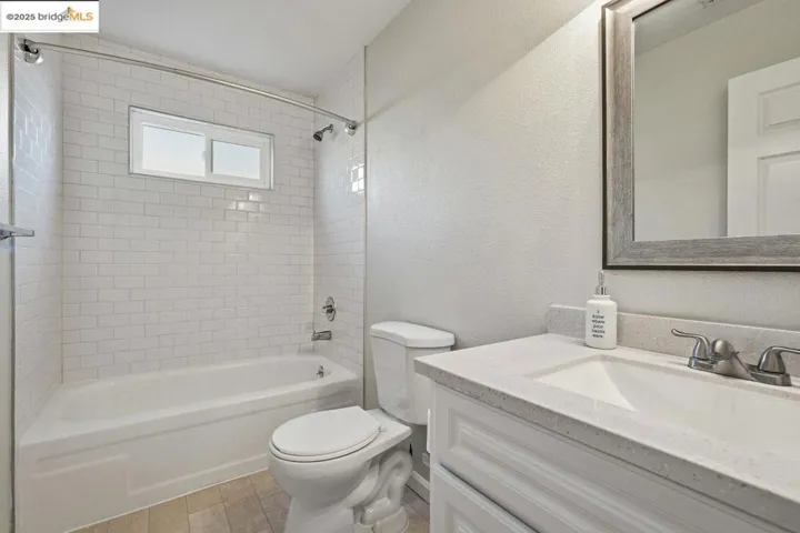 Bathroom with a textured wall, vanity, and shower / bathtub combination