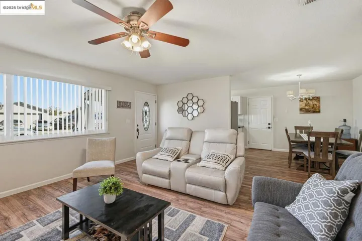 Living area with wood finished floors, a ceiling fan, and a chandelier