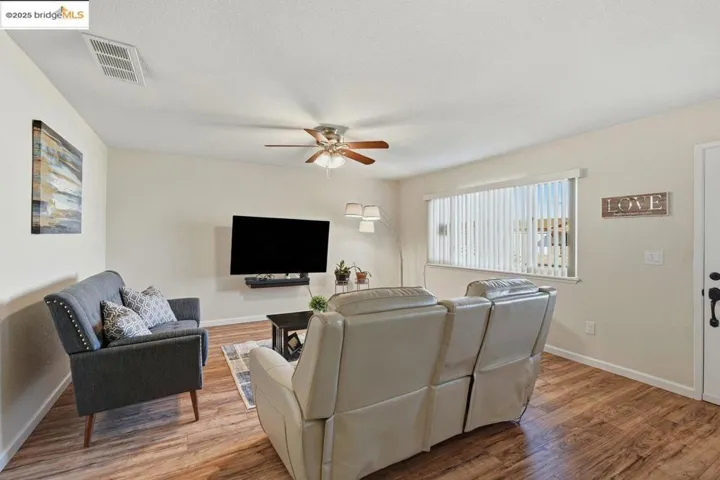 Living room with light wood-style flooring, a ceiling fan, and a textured ceiling
