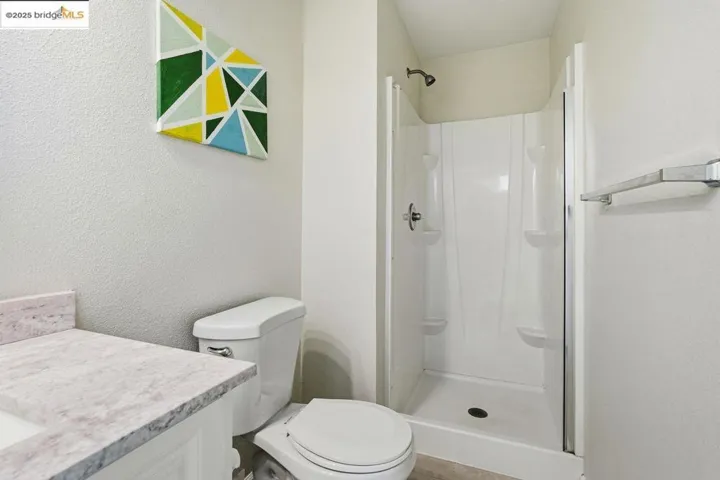 Bathroom with a shower stall, vanity, and a textured wall