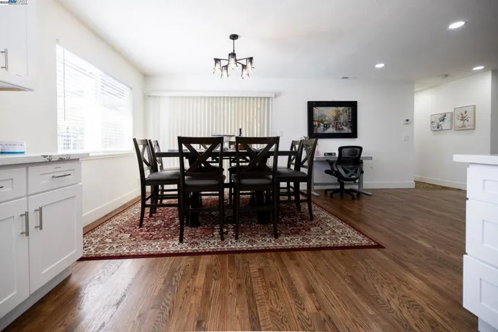 Elegant dining room with a contemporary chandelier, generous natural light, and an open floor plan ideal for entertaining. All furnishings and appliances are part of the sale.