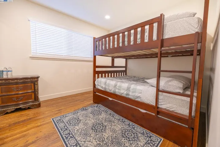 Cozy and well-kept bedroom featuring hardwood floors, recessed lighting, and a sturdy bunk-bed setup ideal for kids or guests. Includes a classic nightstand and area rug that add comfort and character. Furniture Included.