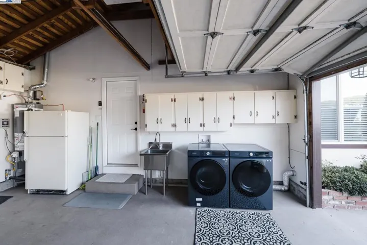 Spacious 2-car garage with overhead cabinetry, stainless utility sink, and premium Samsung washer/dryer. Additional 2-car carport parking in front adds convenience and flexibility. Clean, organized, and functional. Appliances Included.