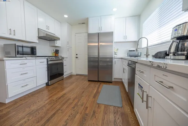 Contemporary kitchen featuring quartz counters, custom cabinetry, and premium stainless appliances. Filled with natural light and designed for function and style — all appliances and included furniture are part of the purchase price.