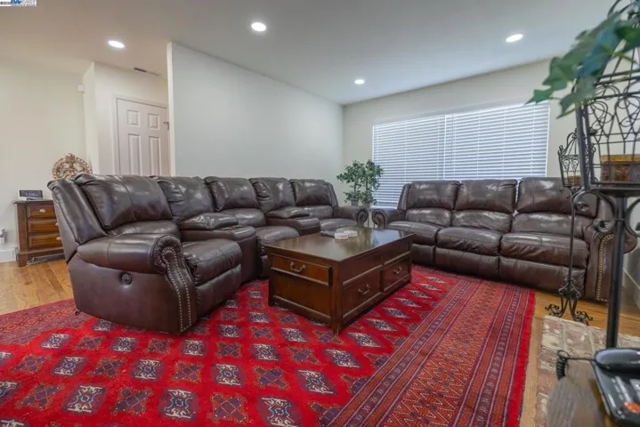 Comfortable living room offering leather sofas, a central coffee table, hardwood flooring, recessed lighting, and plenty of natural light. A charming brick fireplace anchors the space, making it ideal for relaxing or entertaining. Furniture Included.