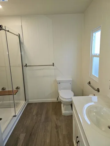 Low flush stylish toilet with safety bars and towel racks nearby.