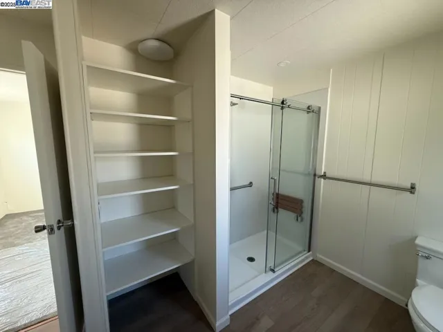 Completely renovated bath with walk in shower and bench.  Linen shelves and luxury vinyl plank flooring.