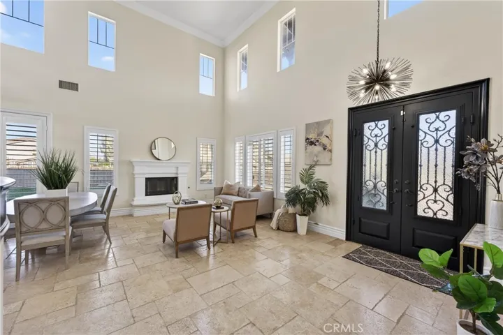 Enter through the grand wrought-iron double doors with textured glass, to the formal living/dining room with tile floor and plantation shutters