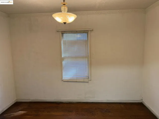 Spare room with dark wood-type flooring and baseboards