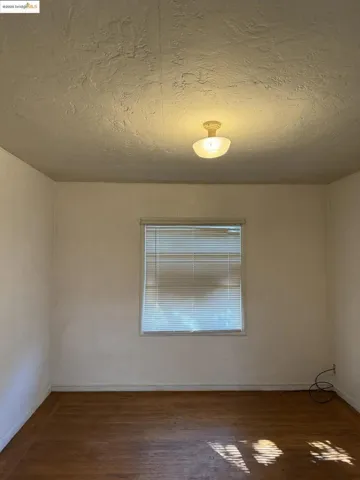 Empty room with a textured ceiling and dark wood finished floors