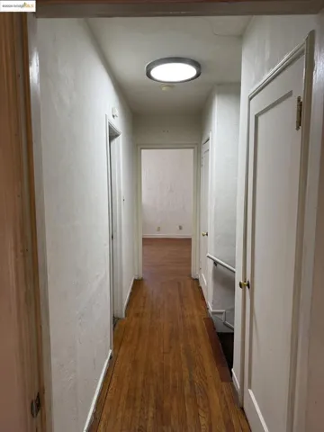 Hall featuring a textured wall and dark wood-style flooring