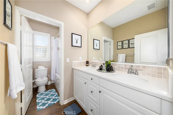 The upstairs bathroom features dual sinks, a custom backsplash, and a shower and tub for added convenience.
