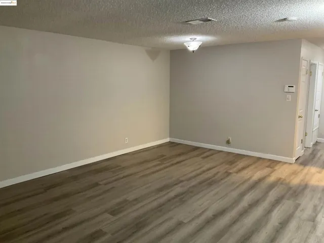 Empty room with dark wood-type flooring and a textured ceiling