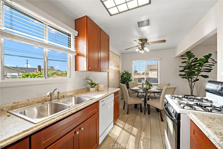 double stainless sinks, a gas stove, and a dishwasher, with an adjacent sunlit dining area