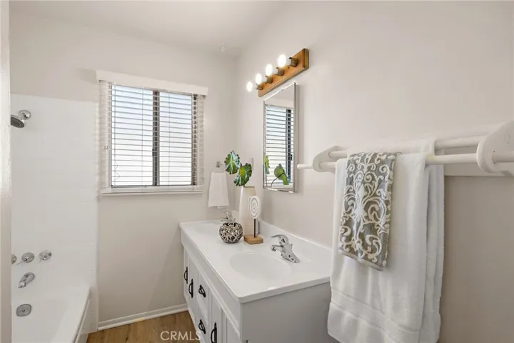 hall bathroom includes new wood vinyl flooring, dual sinks, and a tiled tub/shower combo