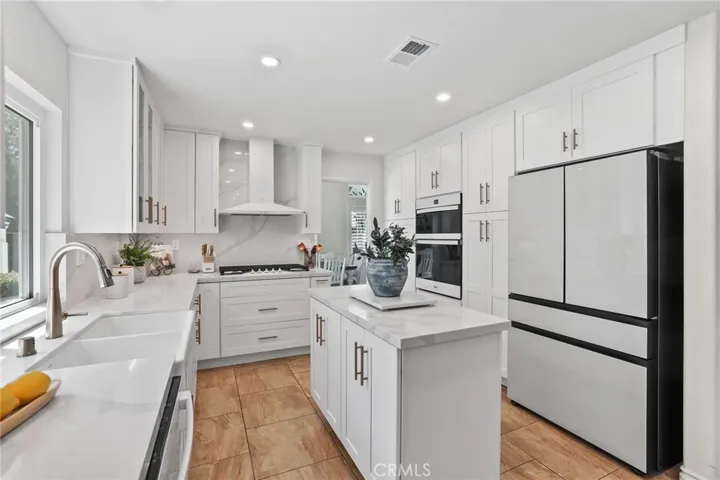 Bright and modern kitchen with white cabinetry, stainless steel appliances, and hardwood floors.