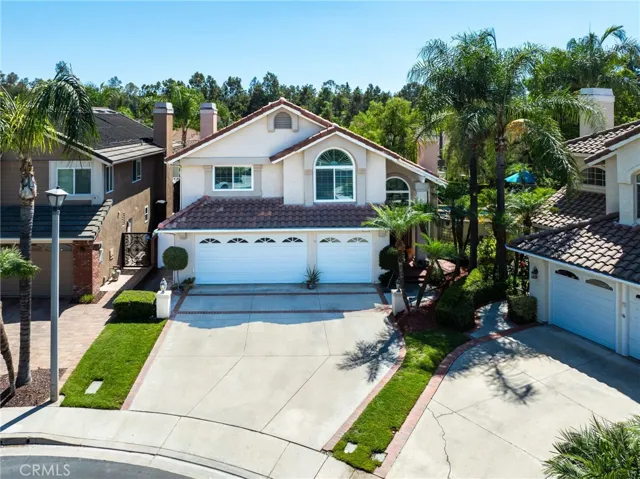 Angled exterior view highlighting the spacious driveway and lush surroundings.
