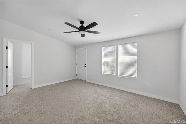 The living room and front door. The door on the left is Secondary Bedroom #1. The white disc on the ceiling to the right of the ceiling fan is one of the fire sprinklers that this home is fully equipped with.