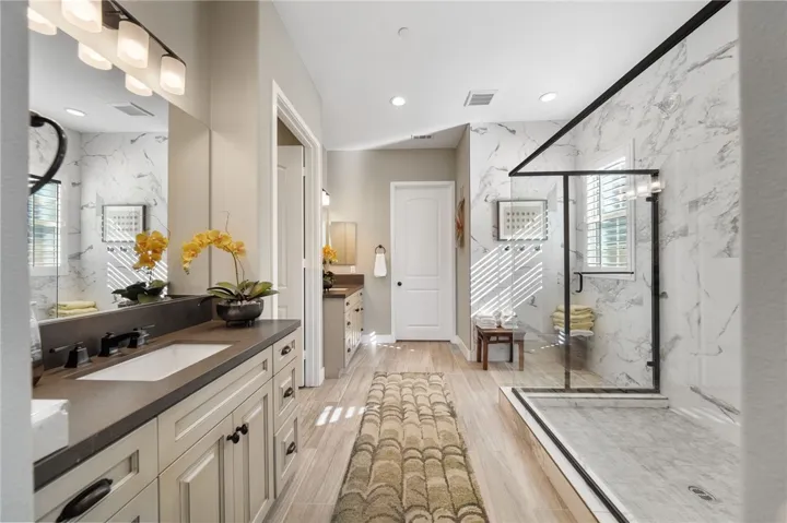 Modern, upgraded primary bath with dual sinks, massive walk in shower and leads to huge walk-in closet.