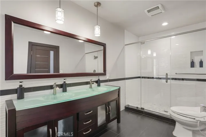 Luxury primary suite with glass-topped dual vanity and oversized shower