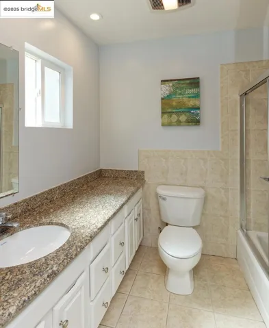 Bathroom featuring tiled shower / bath, vanity, light tile patterned flooring, and tile walls