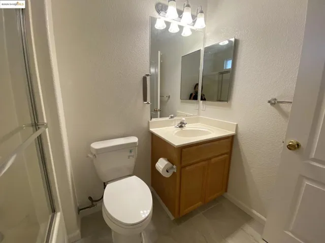 Bathroom featuring a textured wall, a stall shower, vanity, and light tile patterned floors