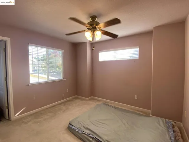 Unfurnished bedroom with ceiling fan, light carpet, and a textured ceiling