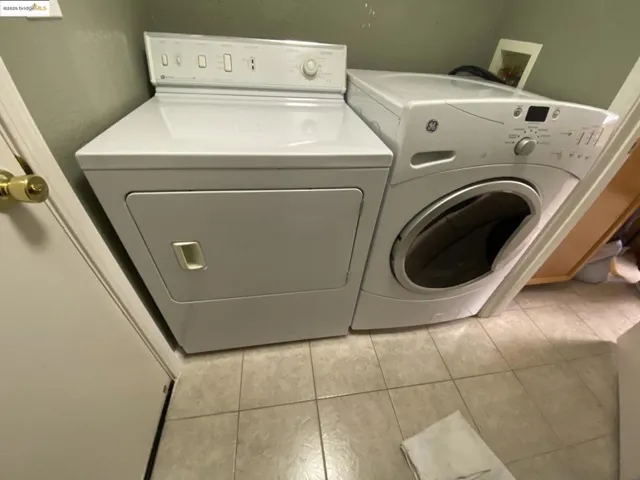 Washroom with washing machine and clothes dryer and tile patterned floors