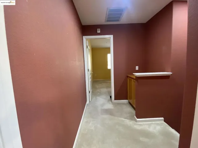 Hallway with baseboards and light carpet