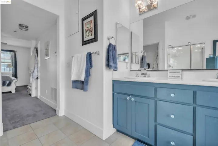 Ensuite bathroom featuring double vanity, a shower stall, and light tile patterned floors