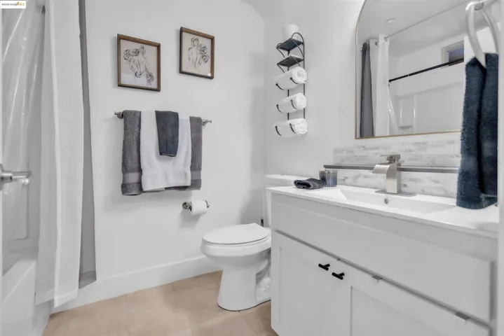 Full bathroom featuring vanity, decorative backsplash, shower / bath combo, and light tile patterned flooring