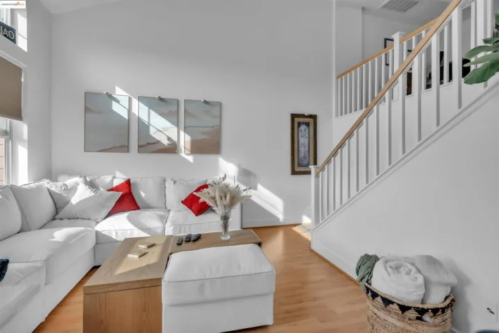 Living room with wood finished floors, stairs, healthy amount of natural light, and a high ceiling