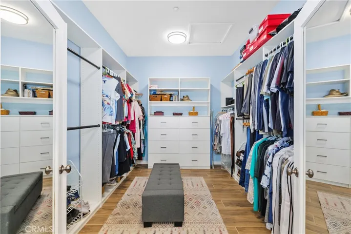 The spacious closet features a double door entry and custom built-in racks and drawers