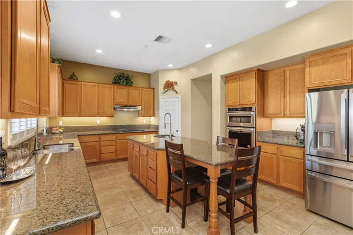 This kitchen is perfect for a busy household. There are granite countertops, and a large island with a prep sink at one end and seating at the other.