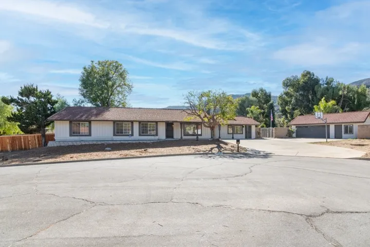 Front of home with expansive driveway and detached garage.