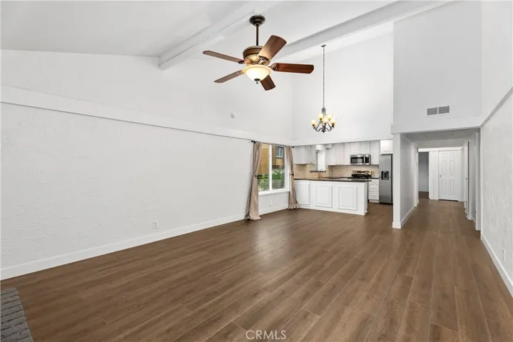 Open concept living room with high ceilings looking into the kitchen.