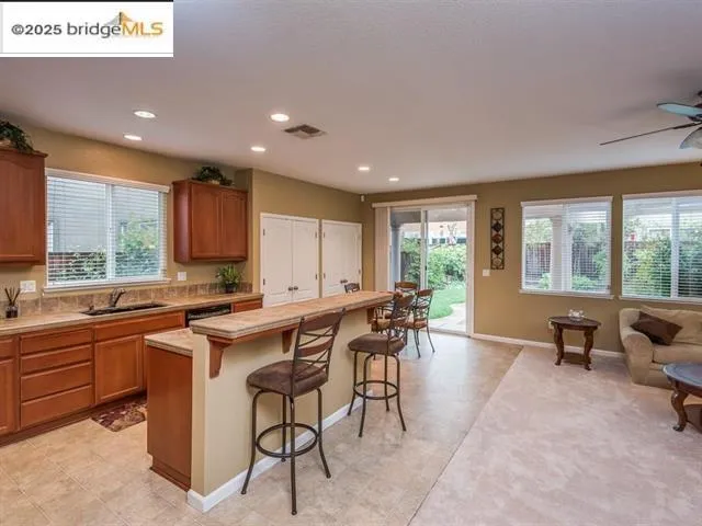Kitchen featuring brown cabinets, light countertops, a breakfast bar, a kitchen island, and recessed lighting
