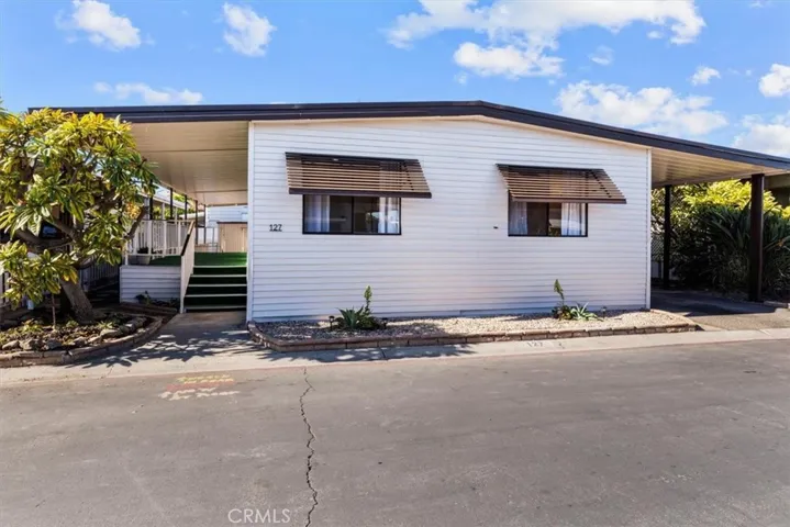 Exterior view of the home at 300 N Rampart St TRAILER 127, Orange, CA. Features a covered porch/carport area and well-maintained landscaping