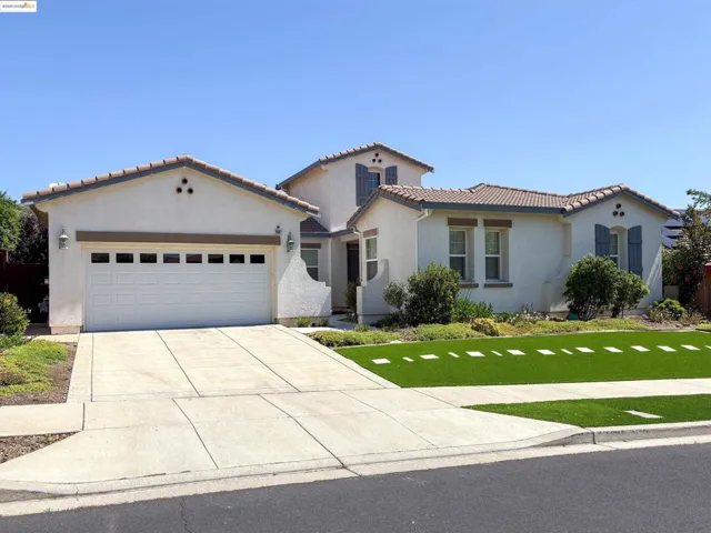 Mediterranean / spanish-style home featuring stucco siding, an attached garage, a front yard, driveway, and a tile roof