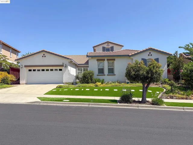 Mediterranean / spanish house featuring a garage, concrete driveway, a front yard, stucco siding, and a tiled roof